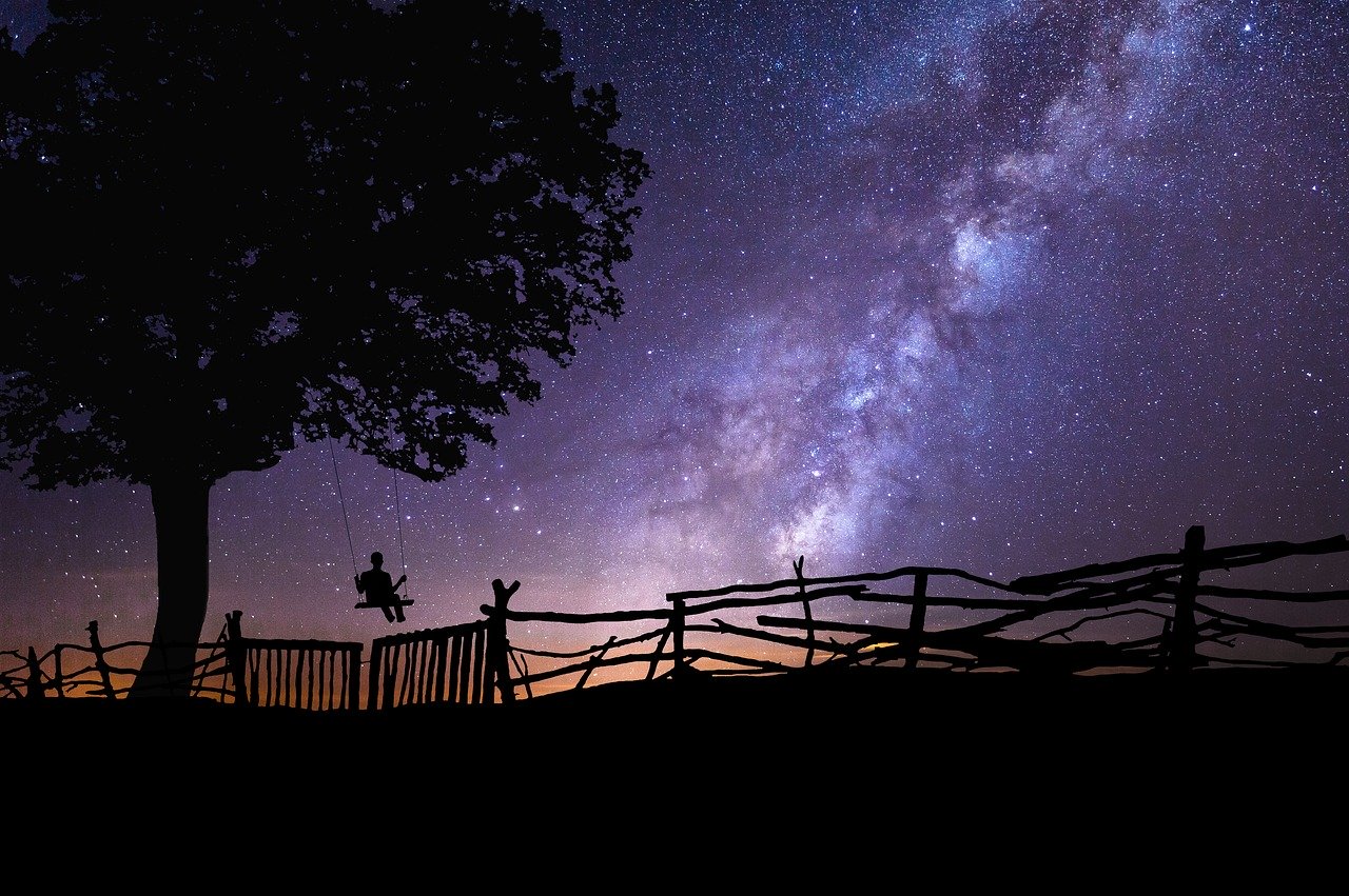child swinging at night looking at stars